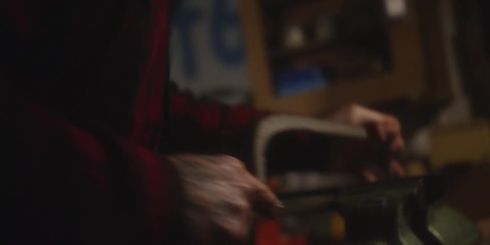 The video features a closeup of a person likely a craftsman or mechanic intensely focused on a task in a dimly lit possibly industrial environment the persons face is seen from above as they work with their hands on a mechanical tool which appears