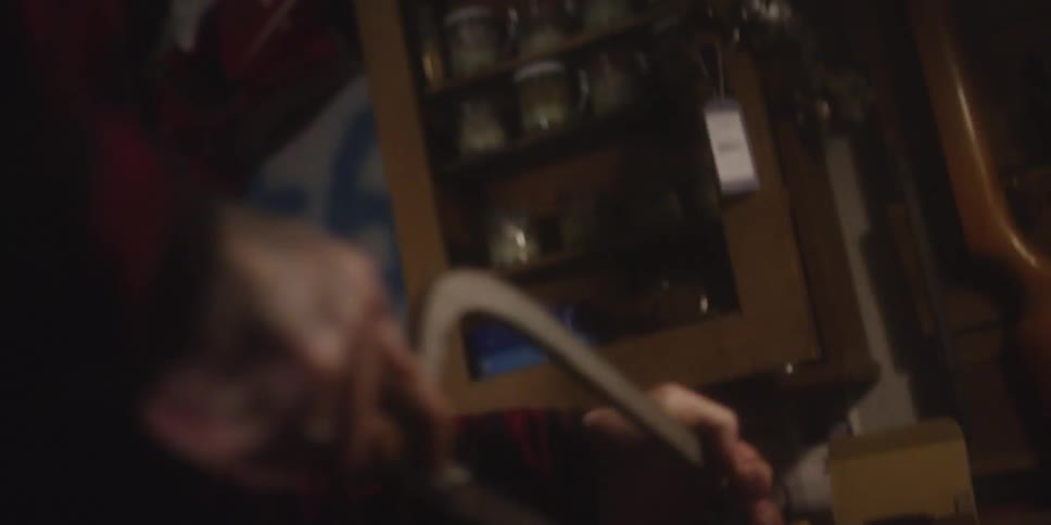 A man uses a hacksaw to vigorously saw at a piece of metal