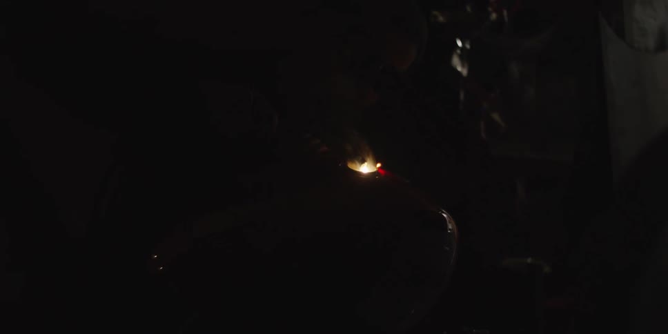 This video features a person in a dark setting likely a workshop welding a metal object that appears to be the fuel tank of a motorcycle which is red and has a yamaha logo visible the bright arc and sparks from the welding process illuminate the wor