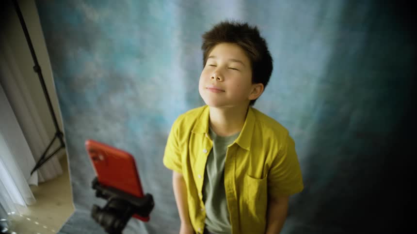 A boy takes a selfie making a funny face in a indoor setting