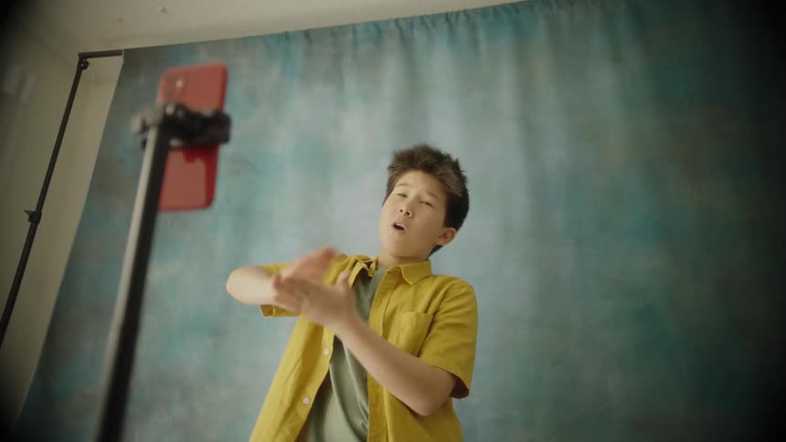 Young boy poses for a picture in front of a cell phone on a selfie stick