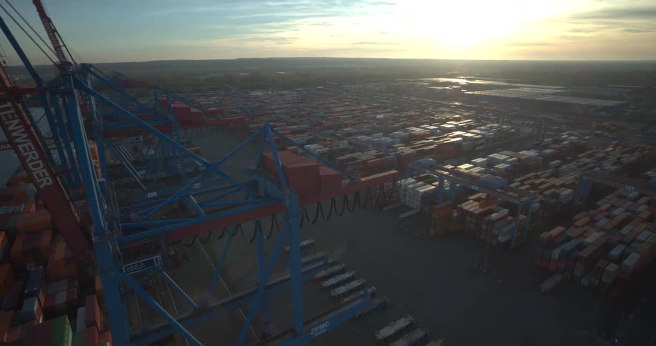 Cargo port with ships and containers next to a city outdoors during dusk or dawn