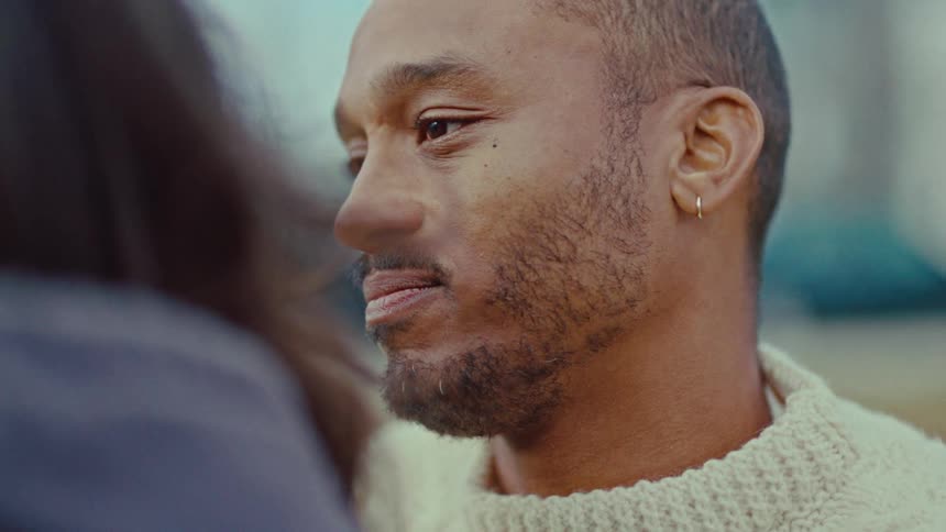 Man in a light sweater in a closeup looking at someone in front of him