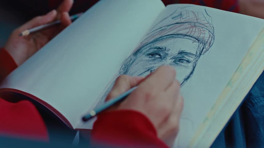 Hand drawing a face in a sketchbook