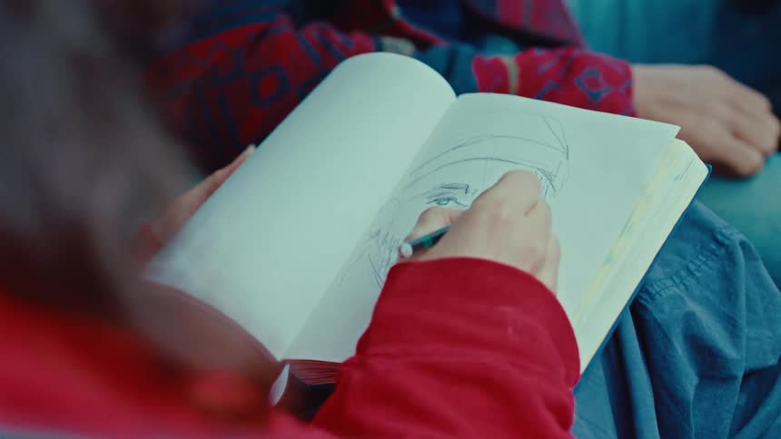 The woman is sketching in her notebook