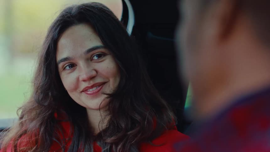 Woman sitting in a car with a man looks over to exchange smiles during the daytime