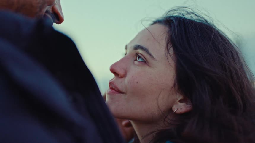 A man lightly caresses the face of his smiling female companion