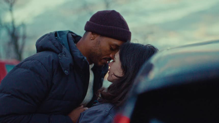 A man kisses a woman against the car
