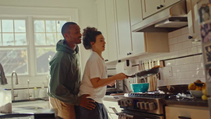 A happy couple cooking together in a sunlit modern kitchen