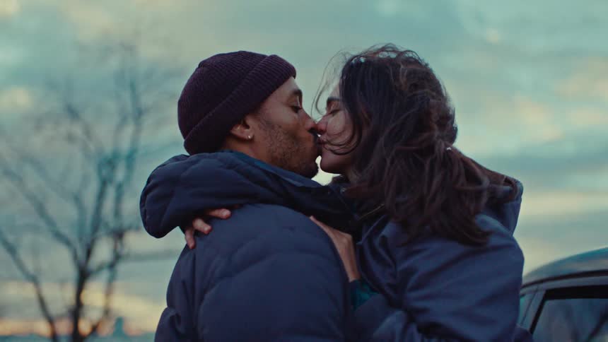A happy couple shares a warm kiss and embrace outdoors at sunset