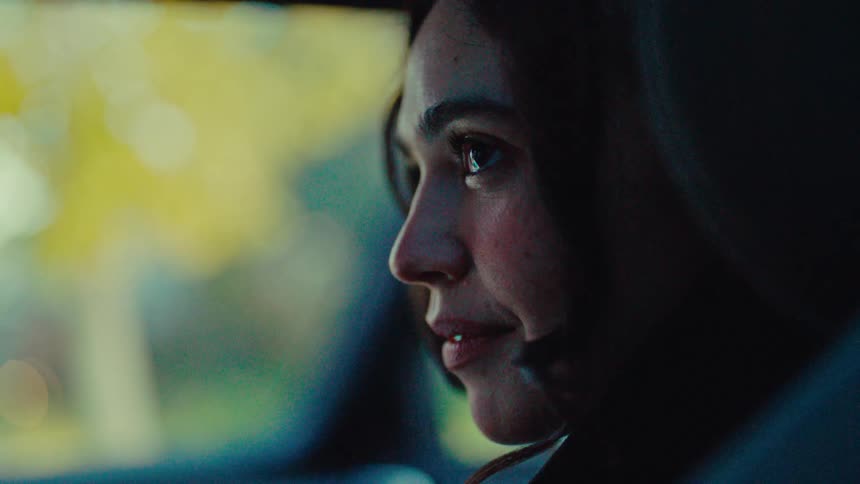 A young woman smiles softly as she has a conversation with someone off camera