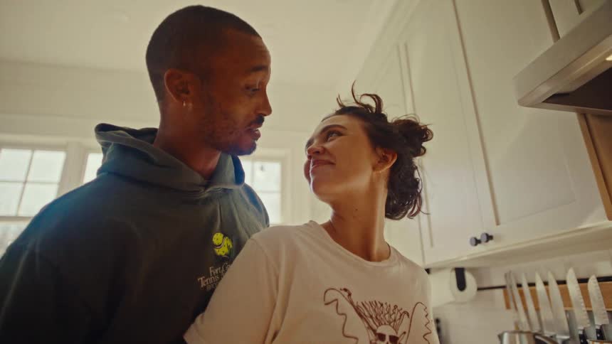 Couple in a kitchen sharing a kiss near the stove