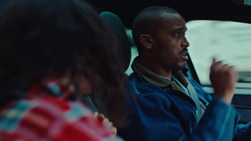 A man and woman sing as they drive
