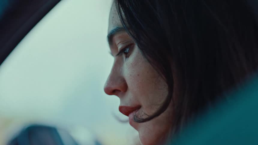 Woman sitting in a car turns her head to look out the side window during the daytime