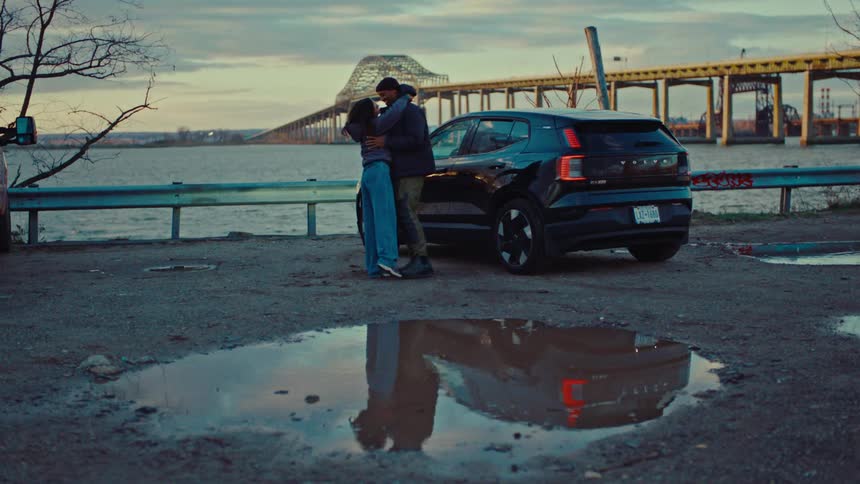 Couple holding hands in a romantic moment next to a car