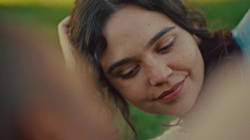 Woman lying outdoors looking at someone offframe