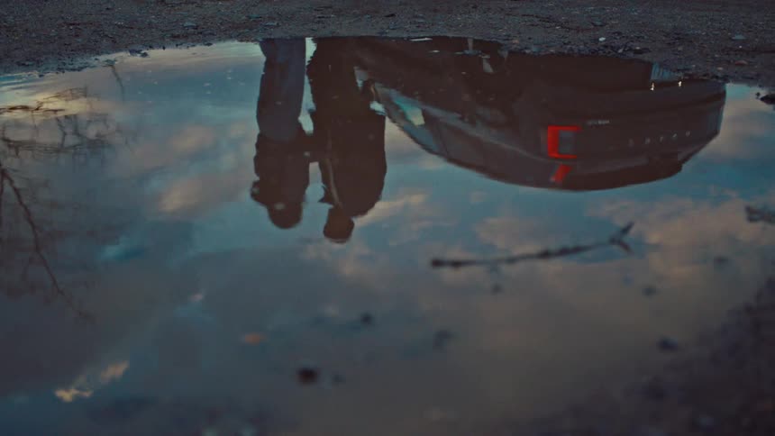 The reflection of the puddle show a man and woman hugging