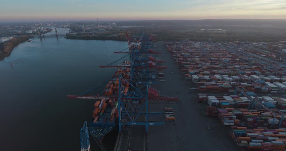 Port terminal at dawn with cranes operating among stacks of containers