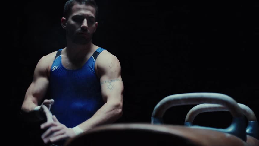 A male athlete rubs his hands together preparing for gymnastics training