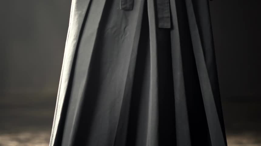 Closeup of dark pleated fabric hanging in a dimly lit space