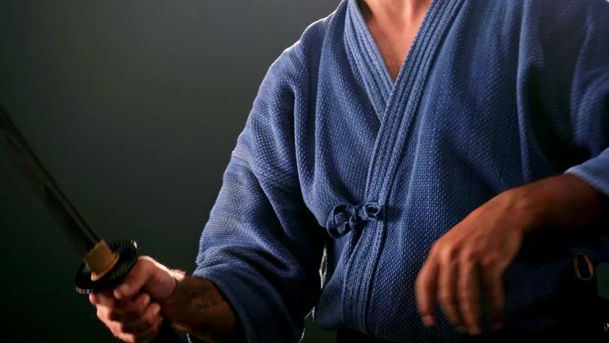 Martial artist wielding a katana while wearing a traditional blue uniform