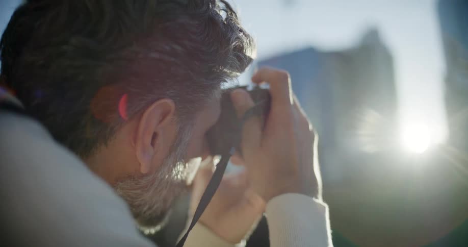 Man holding a camera in shooting position with a beam of sunlight crossing the frame