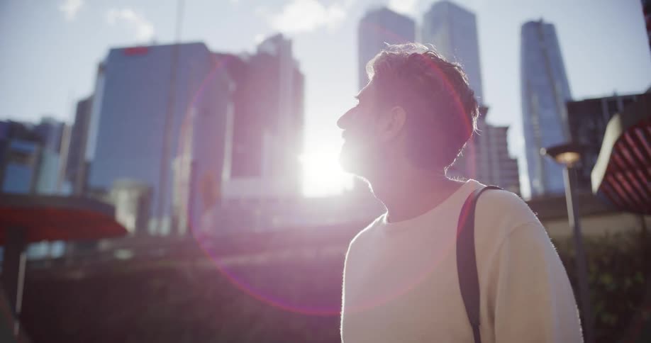 Man walking in an urban area with sunlight lens flare behind his head