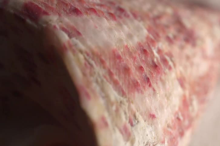 The videos showcase closeup macro shots of natural textures highlighting their surface details and coloration one video features a rough speckled pink and white surface while the other shows the smooth iridescent purplishpink interior of a seashe