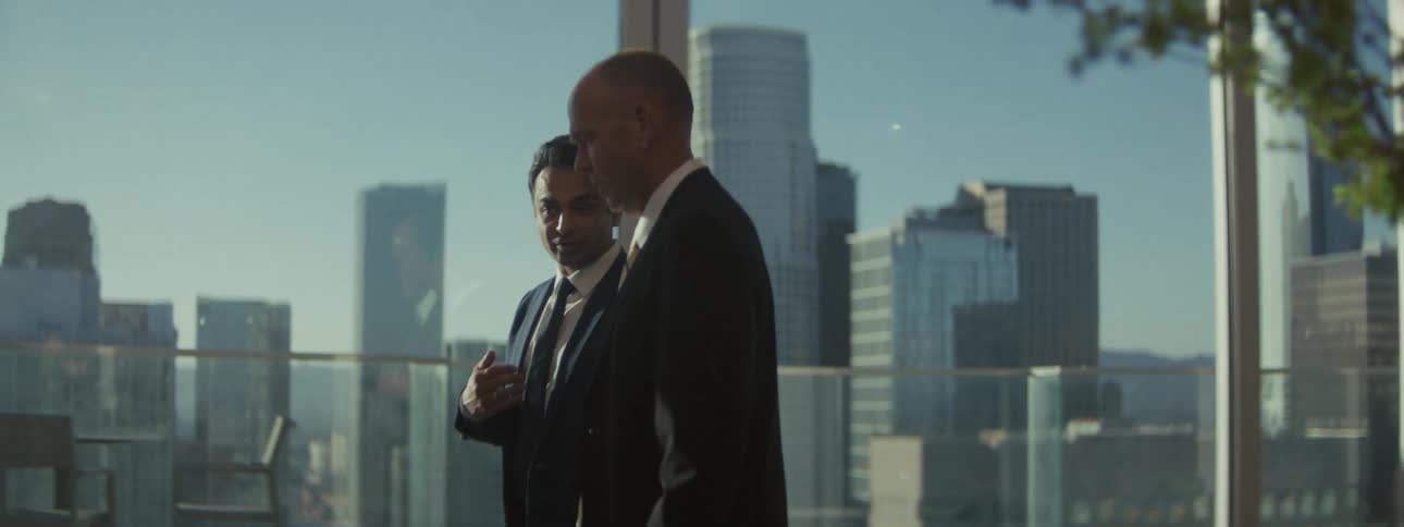Two men walk and talk in an office