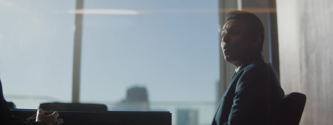 Man in a suit sitting near a window in a corporate setting
