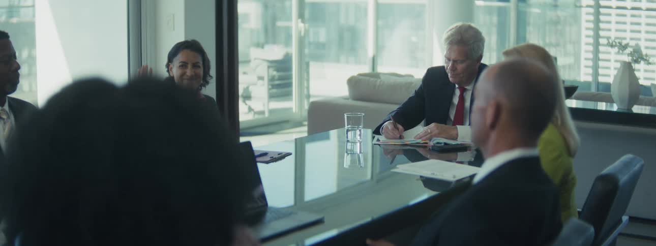 Group of professionals gathered in a meeting room with a glass table
