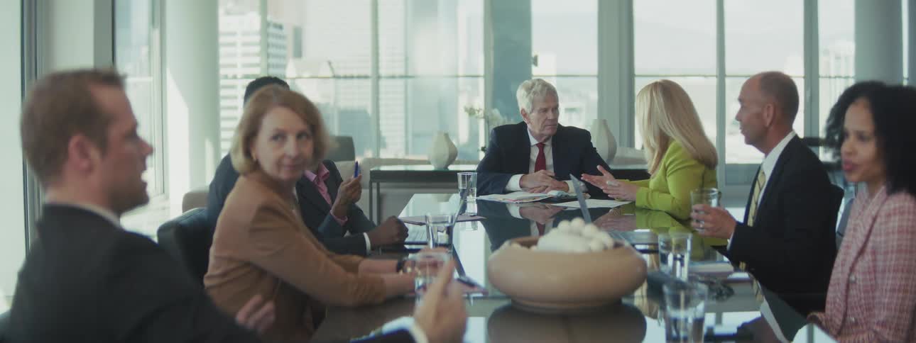 Professionals seated around a meeting table with documents and laptops