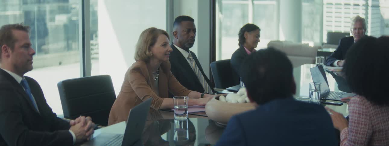 Professionals gathered around a glass table in a corporate discussion