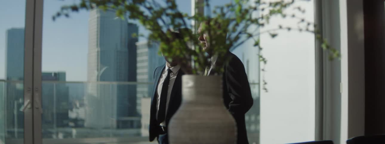 Two male executives conversing while walking together in a conference room during daytime