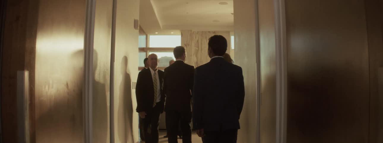 People in formal attire walking and talking in a lit hallway