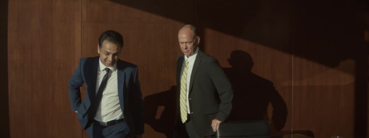 Men in a meeting room beginning to stand up from the table