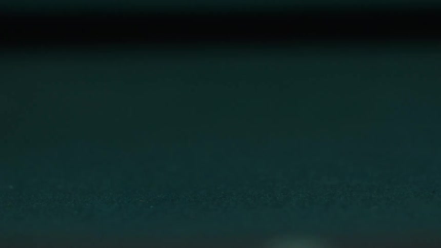A pool cue decisively strikes a white cue ball sending it speeding out of the frame across the dark green felt table