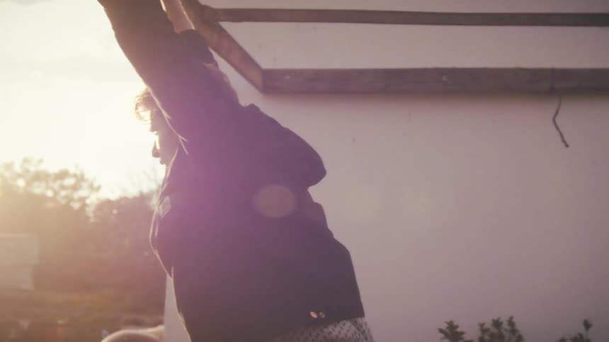 Man standing on his porch with his arms up as he looks ahead