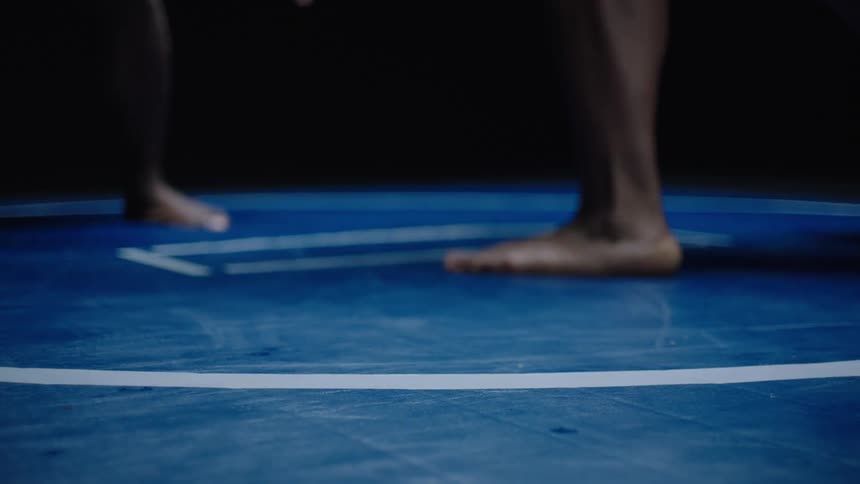 Barefoot athletes legs in a combat circle on a blue mat