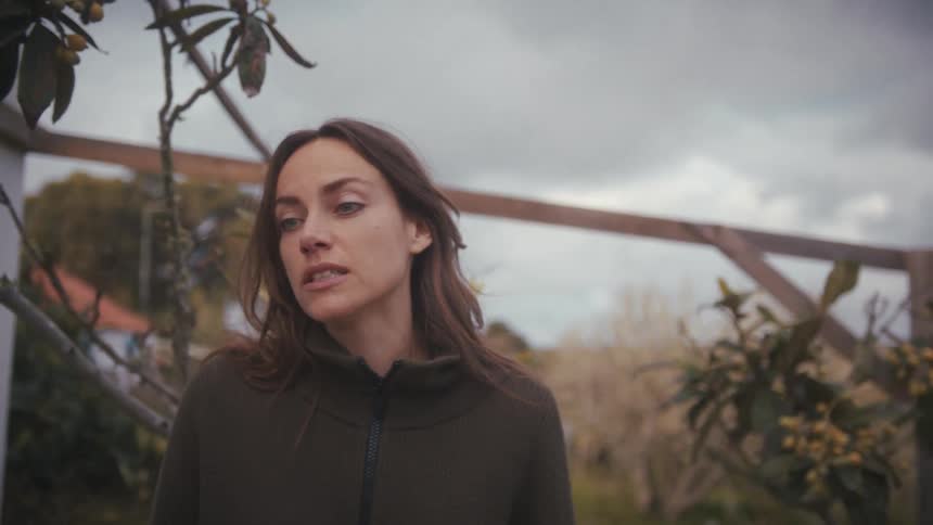 Woman talking in an outdoor area with trees in the background