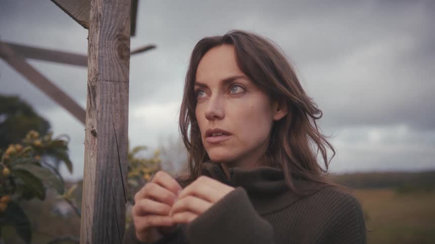 A woman outside by a post