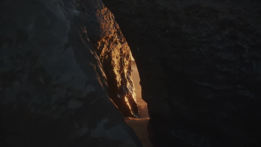 Gap between rocks displaying golden light reflected on the inner wall
