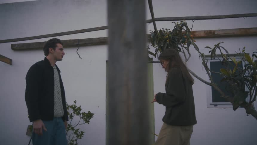 Two people argue in a residential courtyard in front of a house