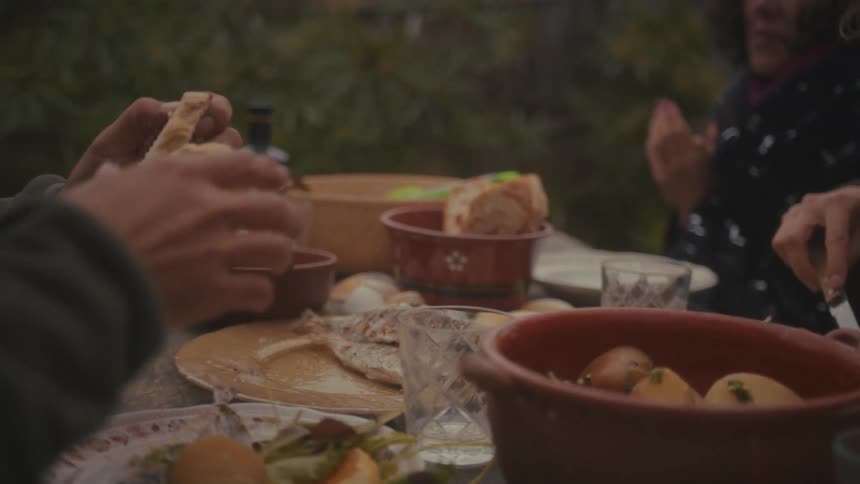 People gathered at a table handling bread and serving food