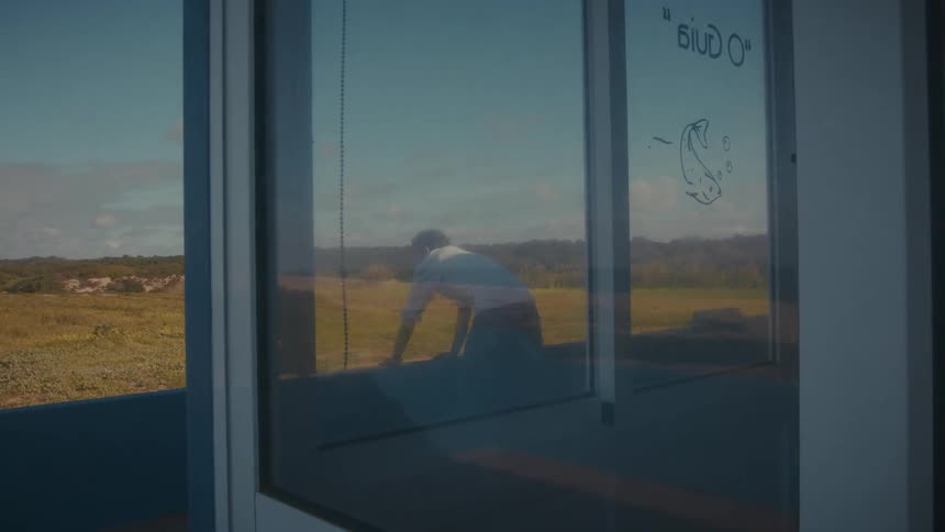 Reflection of a man walking seen on a glass window with a field in the background