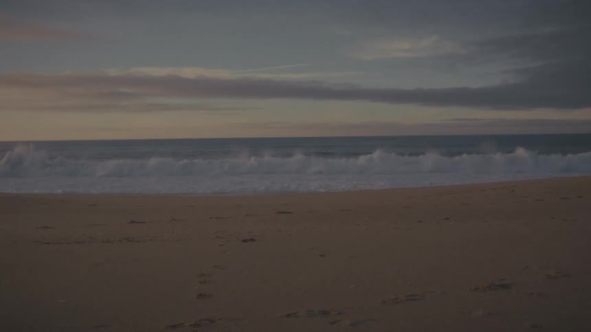 Sunlight illuminating footprints on sand facing the calm sea