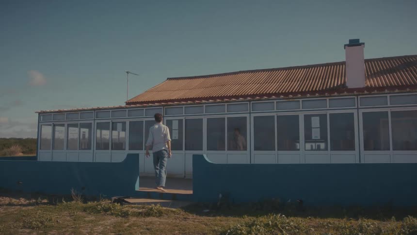 Man walking in front of a glassfronted building with a blue wall