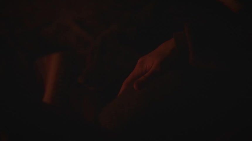 The light from the campfire flickers on the persons hand