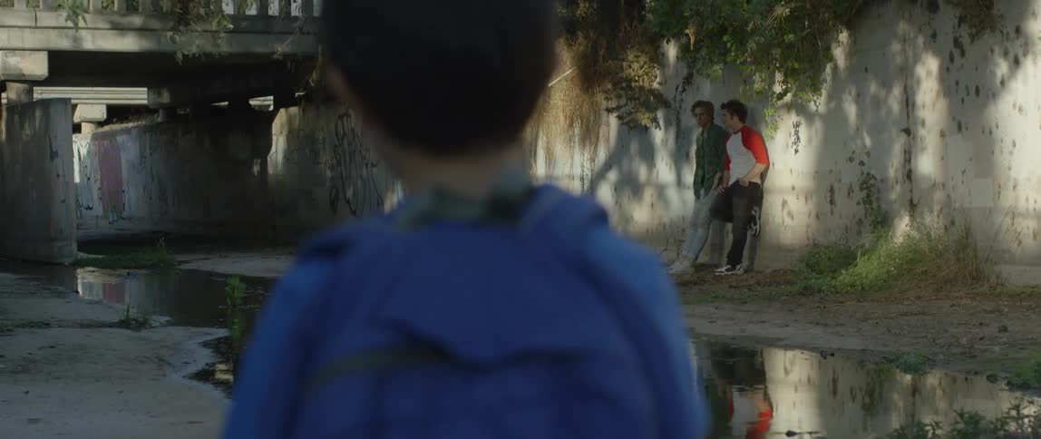 A boy walks past two other boys