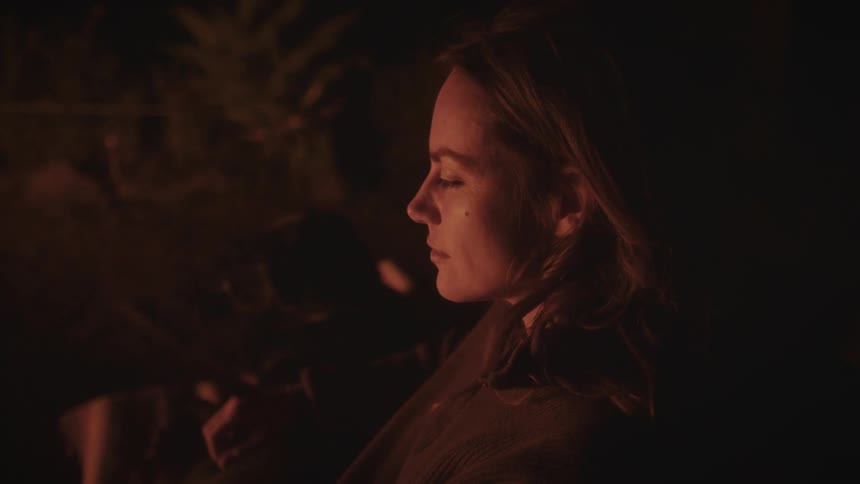 Woman sitting near a warm light source in a dark environment